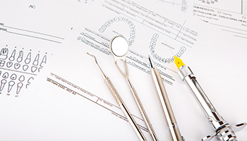 dental tools sitting on dental documents