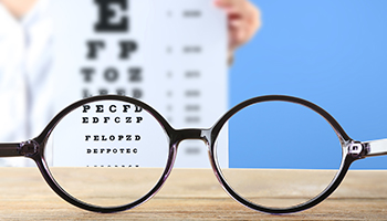 Eye glassed on a wood table with eye sight chart